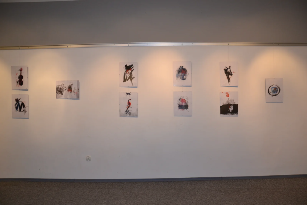 Czarno-białe ilustracje z cyklu Laboratorium ArtDHD w rzędzie na ścianie galerii, wystawa ilustracji Laboratorium ArtDHD, Miejskie Centrum Kultury, Czarnków 2015
