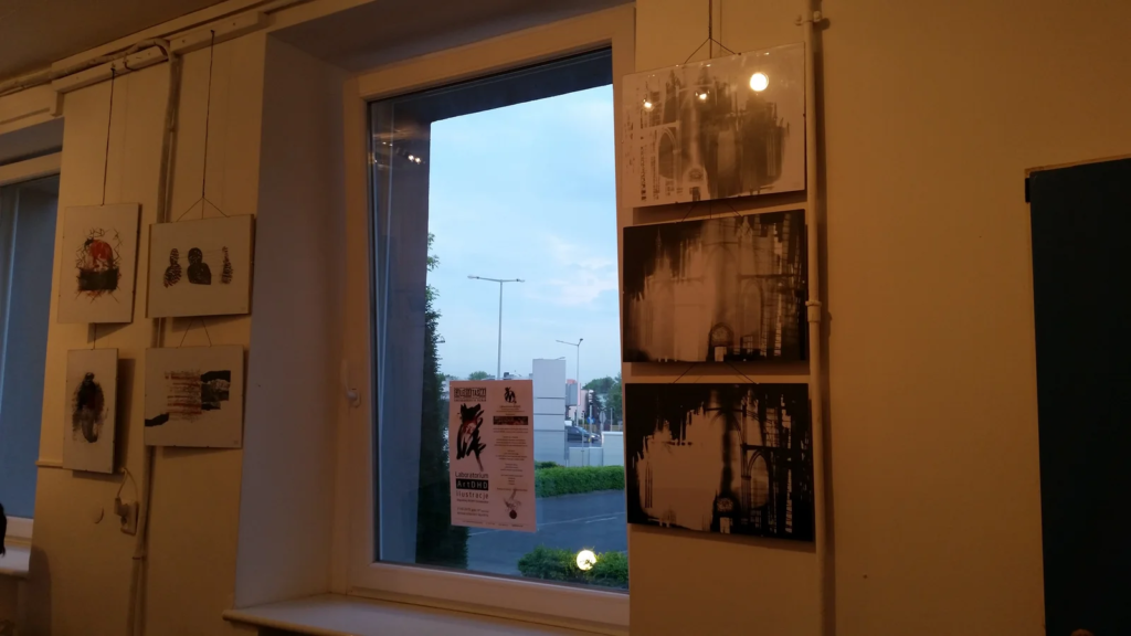 Ilustracje przy oknie galerii wieczorem, wystawa ilustracji Laboratorium ArtDHD, Galeria Sztuki TAŚMA, Poznań 2015