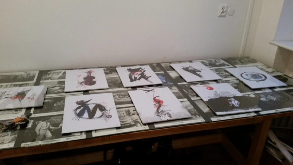 Ilustracje rozłożone na stole przed zawieszeniem, wystawa ilustracji Laboratorium ArtDHD, Galeria Sztuki TAŚMA, Poznań 2015