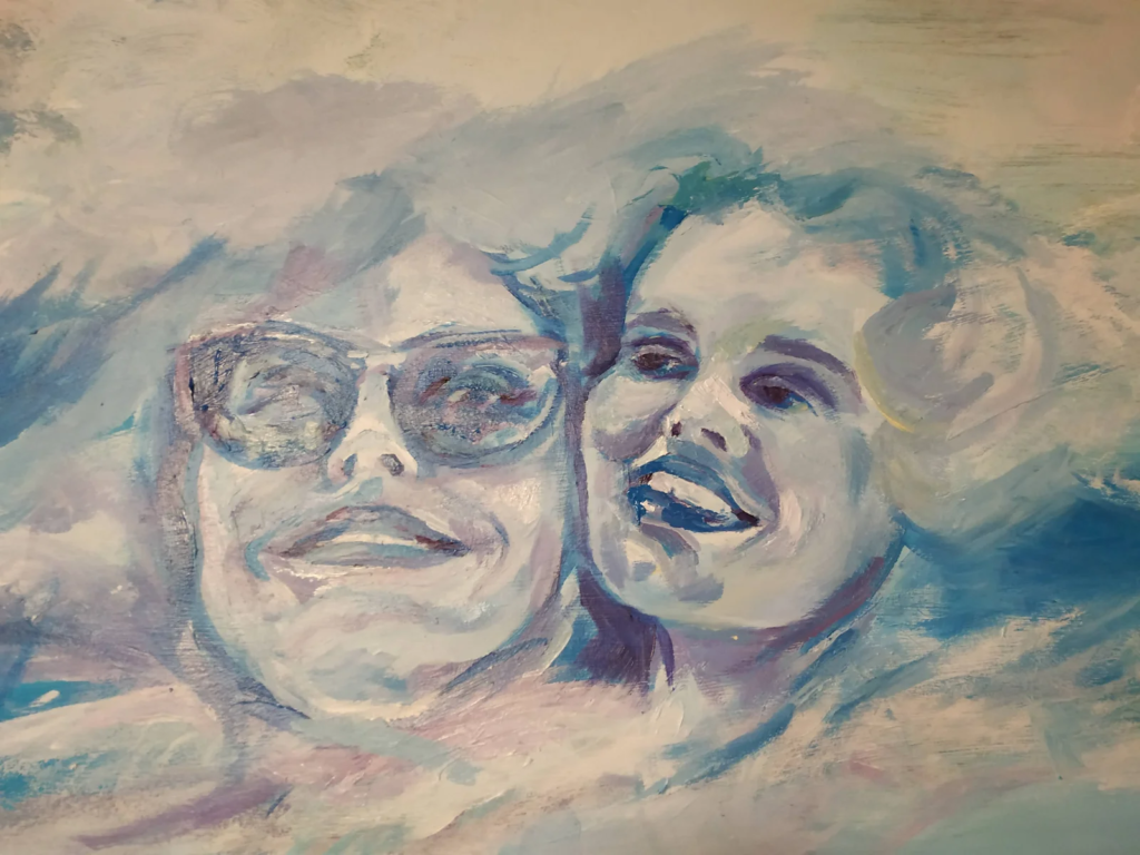 Fragment muralu Thelma & Louise: twarze bohaterek w chmurach nad pustynią